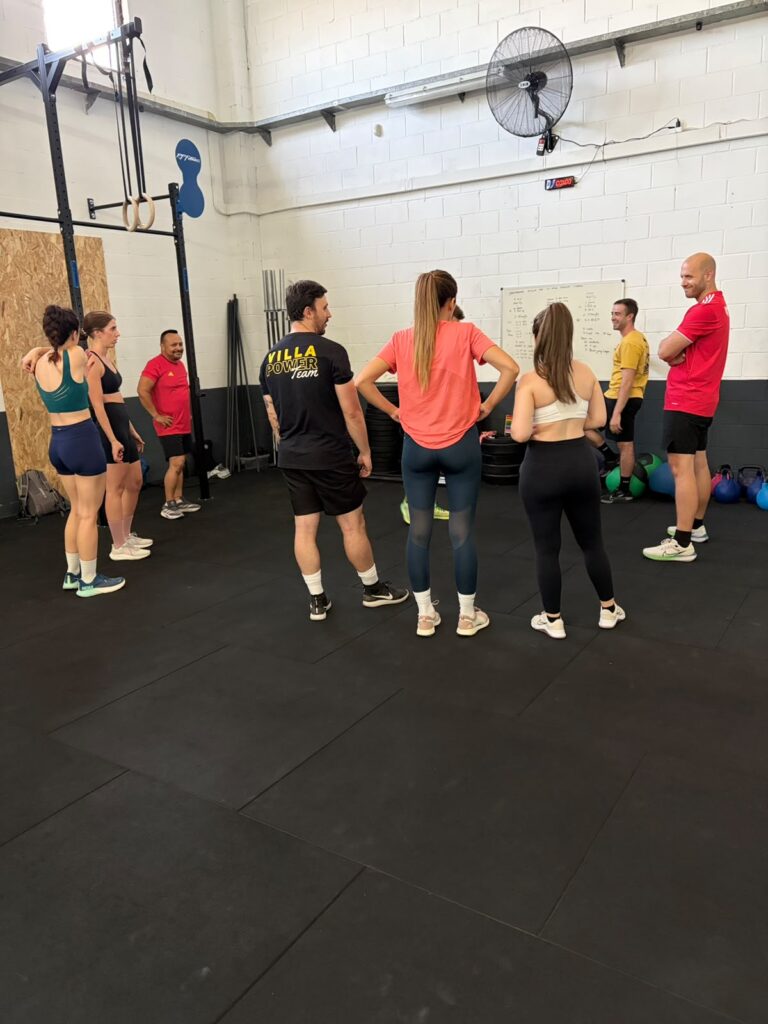 Alumnos escuchando la explicación del entrenador en una clase de crosstraining en La Nave Strength Center